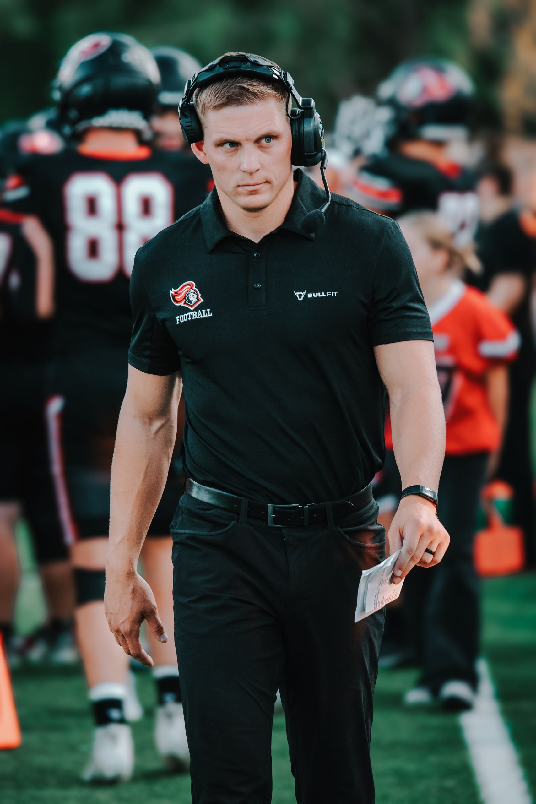 Focused coach on the sidelines during an intense high school football game.