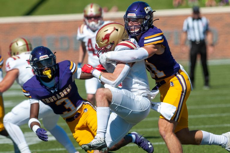 College football players in action, showcasing a dynamic tackle on the field.