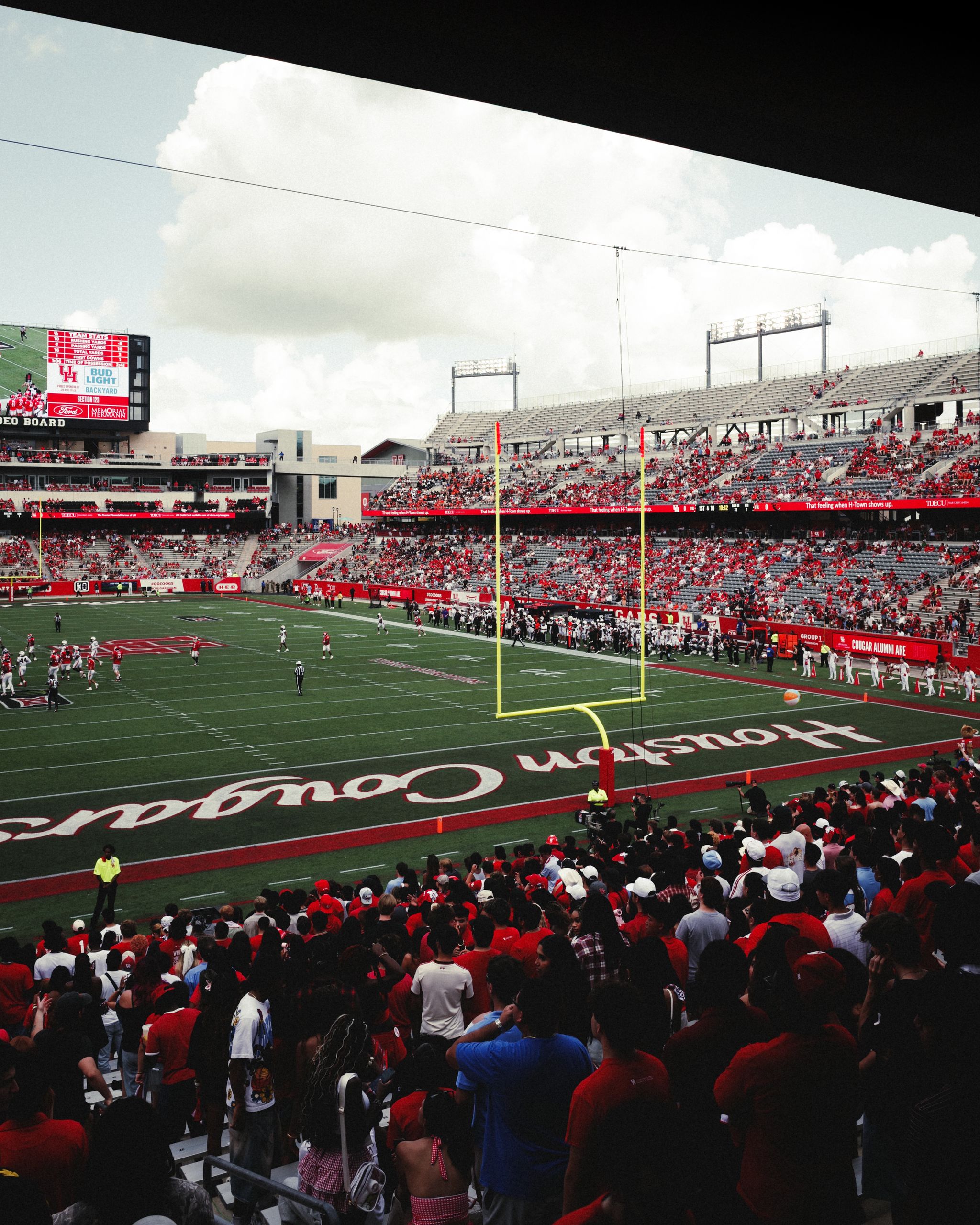 Crowded football stadium in Houston, Texas with lively fans and players on the field.