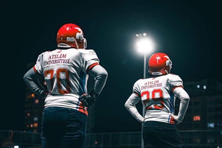 Football players in Atılım University jerseys standing under stadium lights at night.
