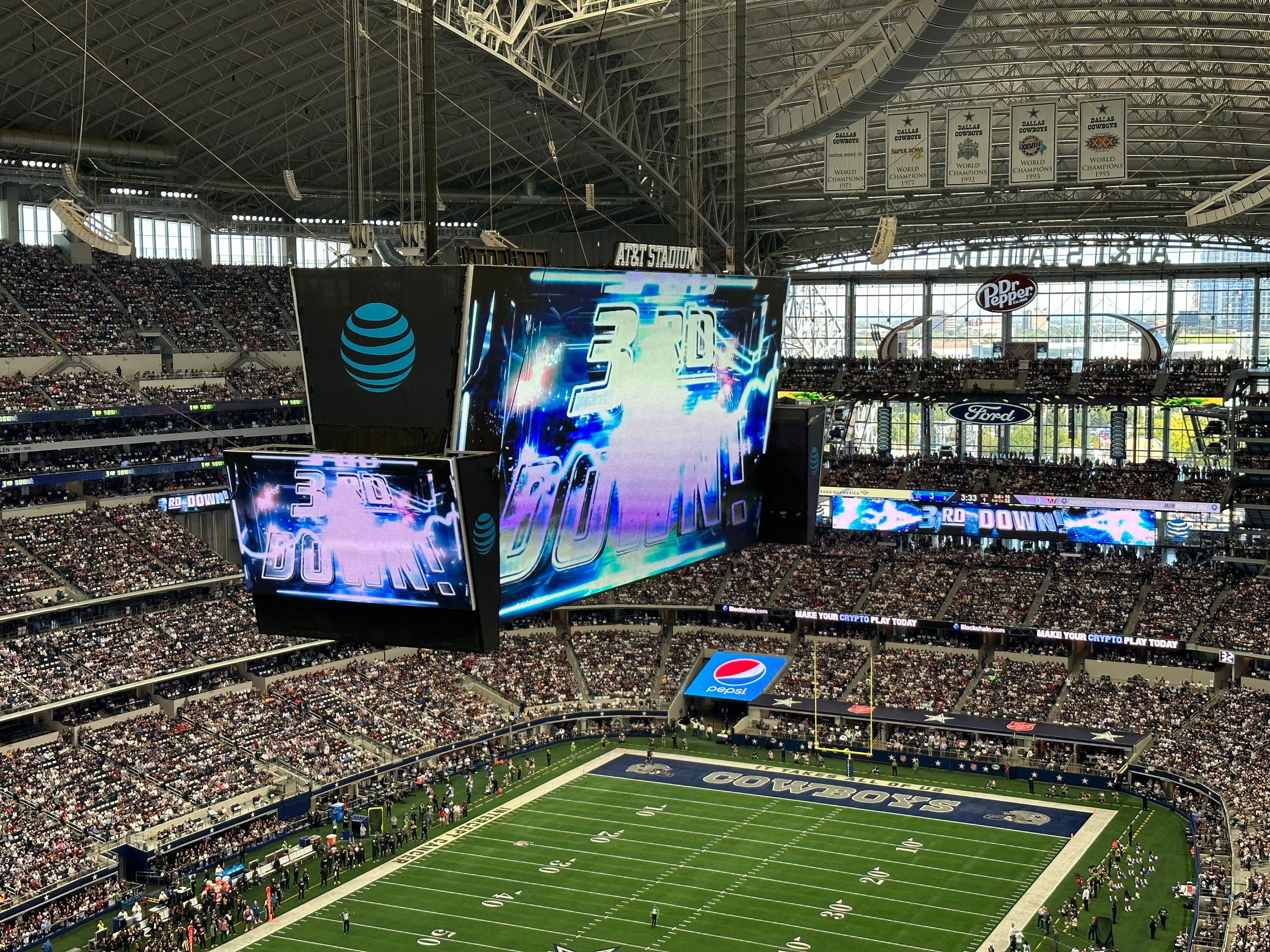 High-energy football game at AT&T Stadium with a massive crowd and electronic displays.