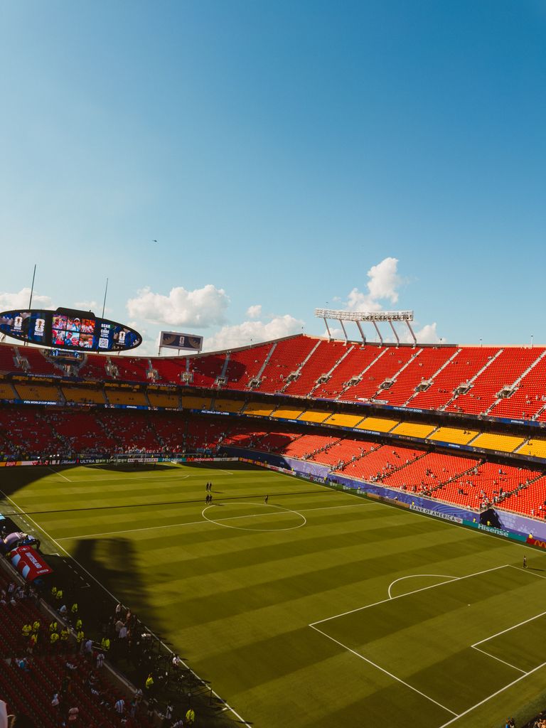 Wide-angle view of a vibrant football stadium on a sunny day with clear blue skies.
