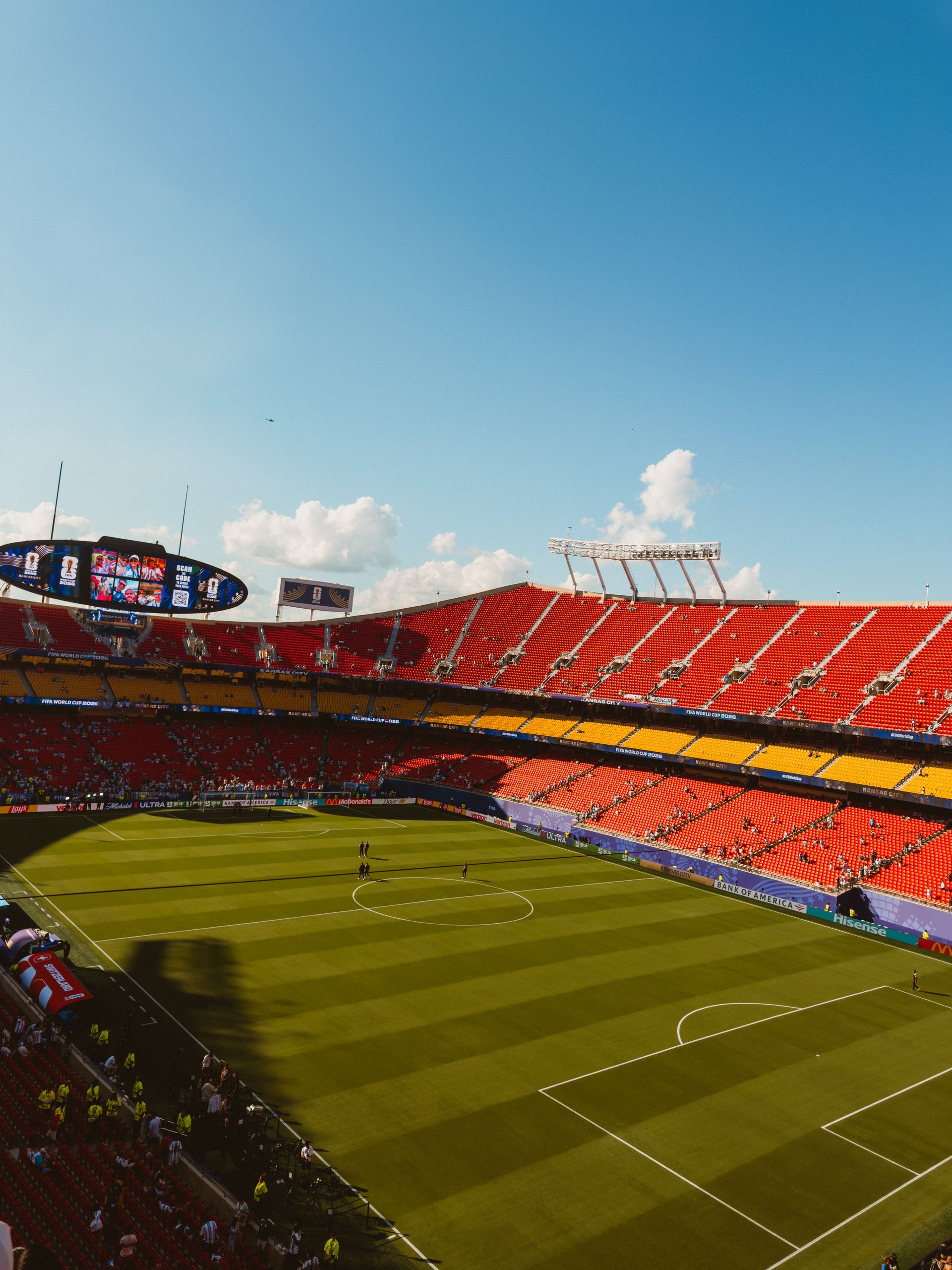 Wide-angle view of a vibrant football stadium on a sunny day with clear blue skies.