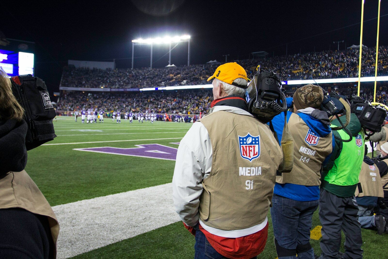 people standing and watching NFL game in green field
