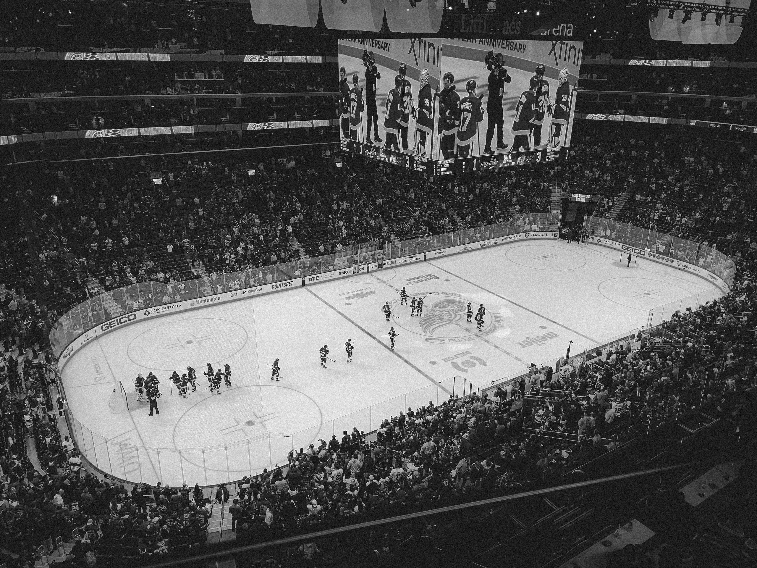 Black and white overhead shot of a thrilling ice hockey game with a full audience in an indoor arena.
