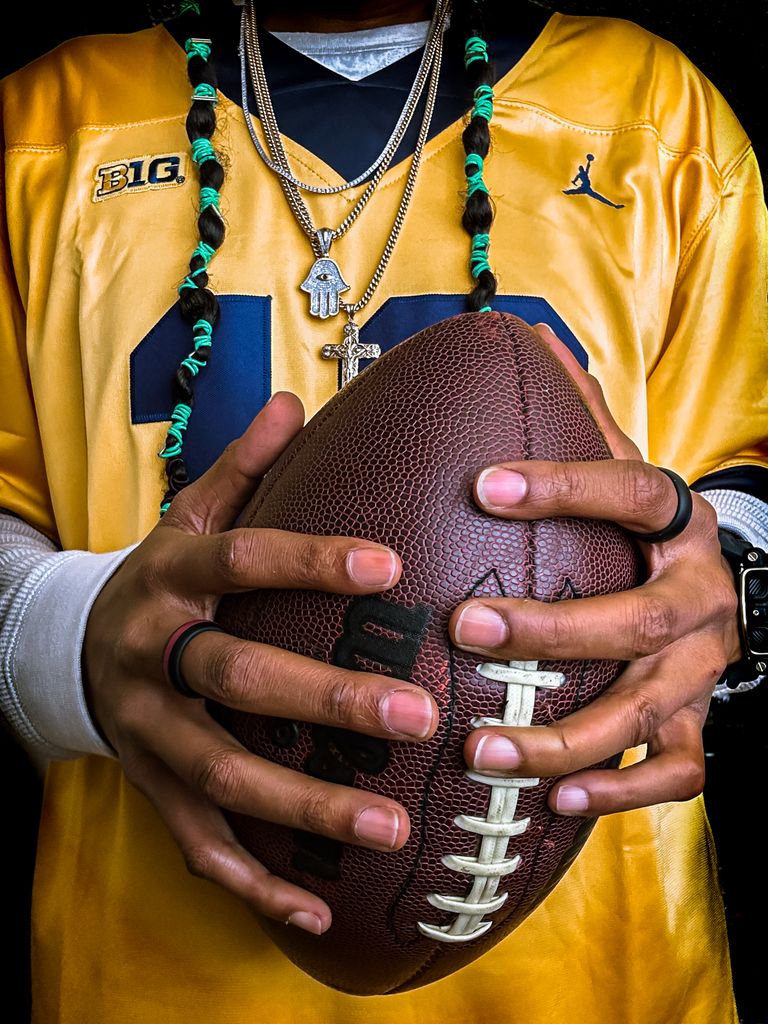 Close-up image of a man's hands gripping an American football, highlighting sportsmanship and focus.