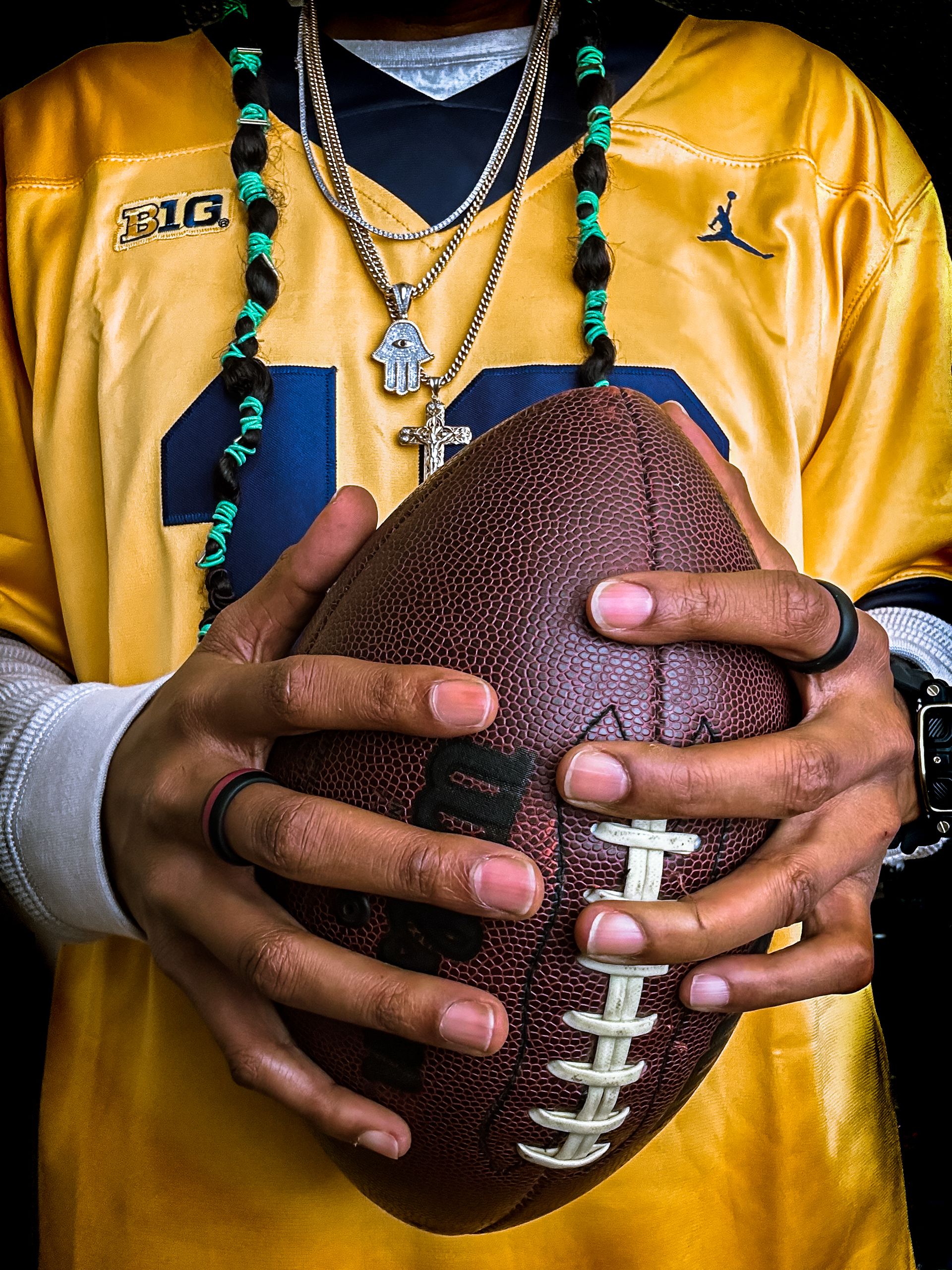 Close-up image of a man's hands gripping an American football, highlighting sportsmanship and focus.