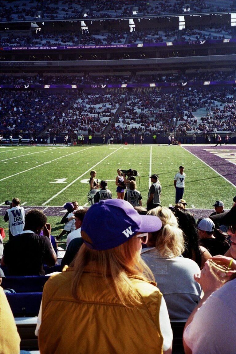 Spectators in a stadium watching a television crew filming on the football field