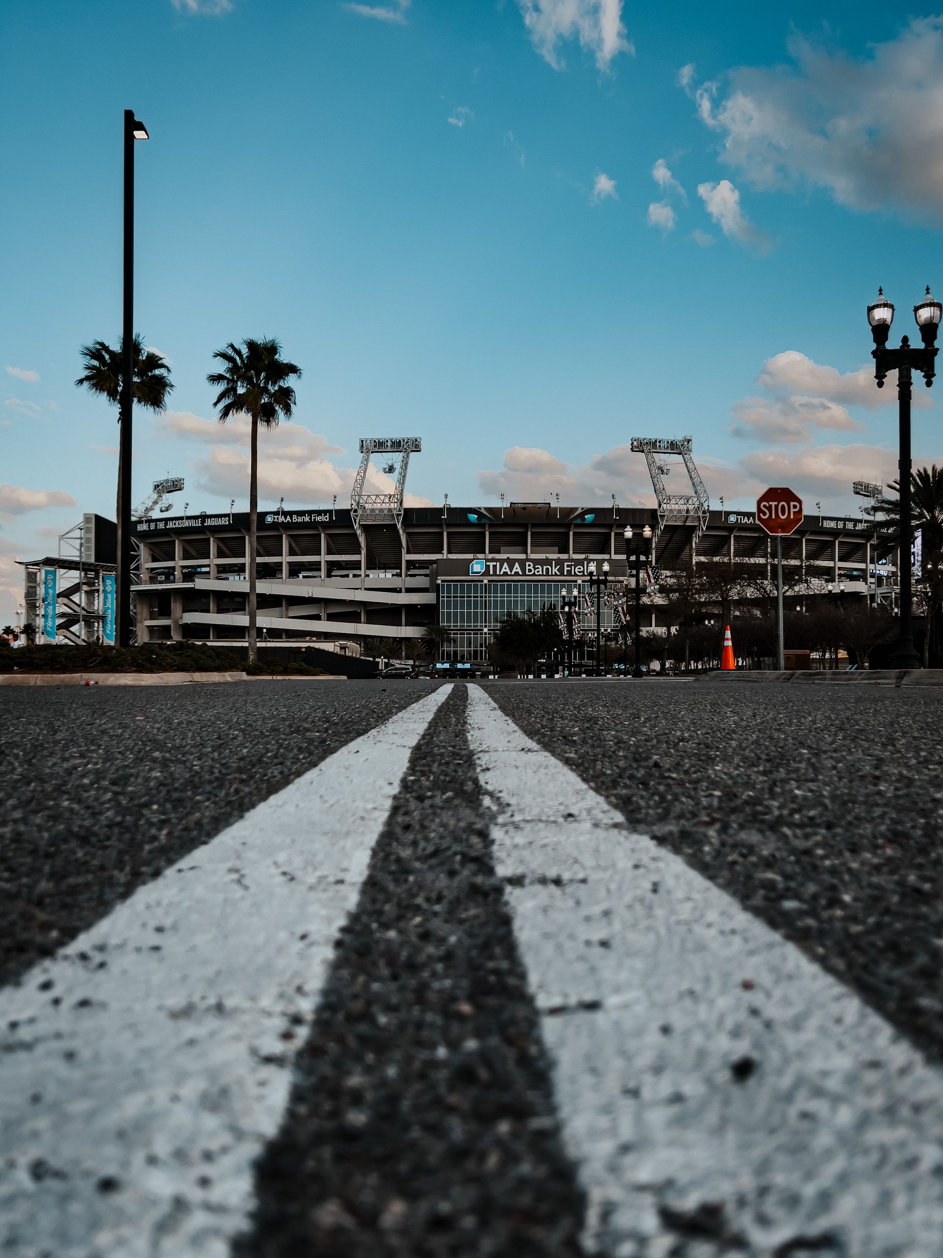 TIAA Bank Field in Jacksonville, Florida, captured from the road with palm trees and clear skies.